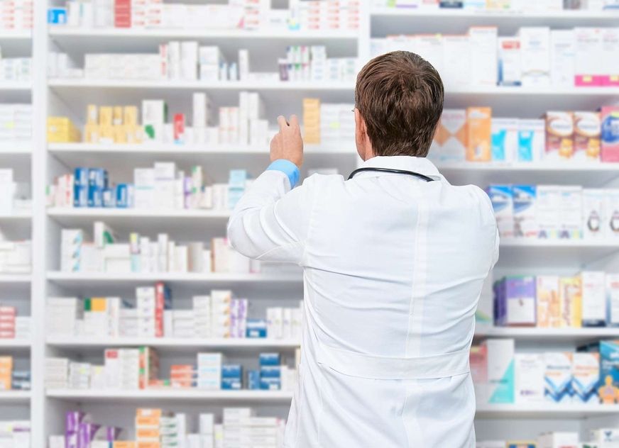 Apotheker sucht ein Medikament und steht am Regal